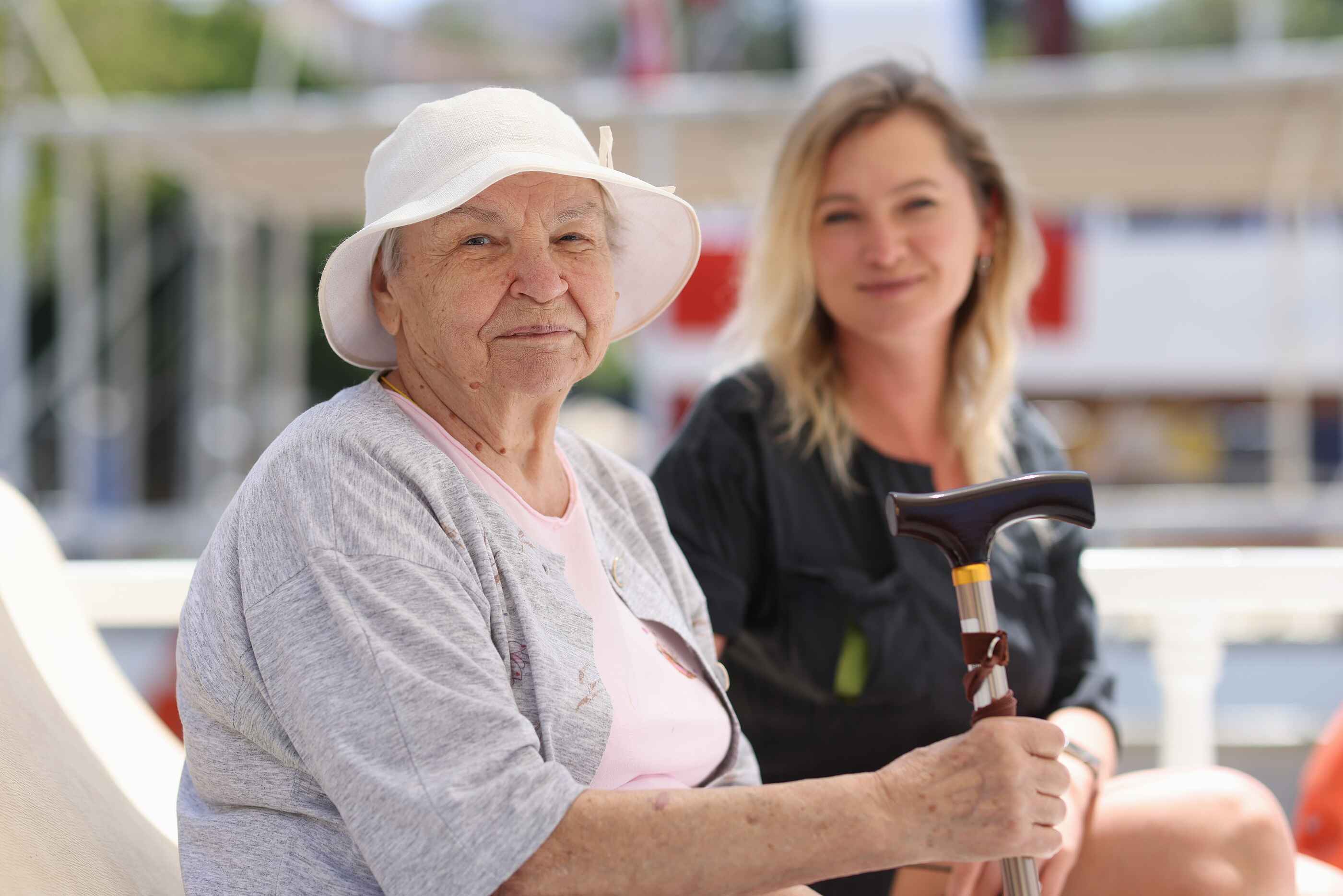 An older person in a hat sits with a younger friend